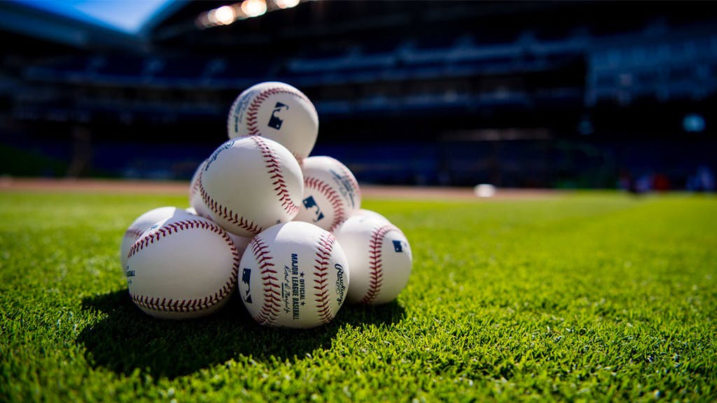 Photo of baseball field with official Major League Baseball balls, background: stadium and green grass